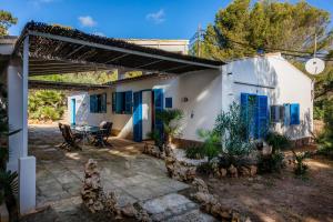 een wit huis met blauwe luiken en een patio bij Finca Es Carregador in Capdepera