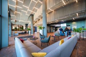 a lobby with couches and chairs and people in a building at Flow Hotel & Conference in Inárcs