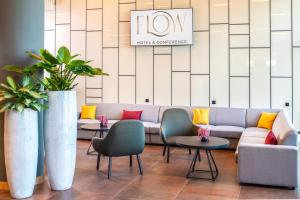 eine Lobby mit einem Sofa, 2 Stühlen und Tischen in der Unterkunft Flow Hotel & Conference in Inárcs