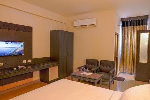 a bedroom with a bed and a table and a tv at Hotel Marvic in Tiruchchirāppalli