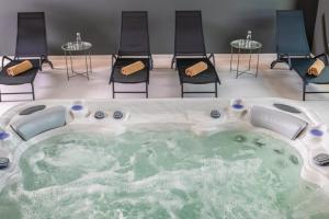 Flow Hotel & Conference في إينارتش: حوض استحمام ساخن في غرفة مع كراسي وطاولات