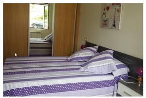 a bed with purple and white sheets and a mirror at Apartamento de 2 habitaciones. in Dor