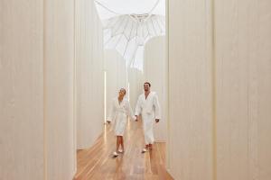 dos mujeres vestidas de blanco caminando por un pasillo en RACV Royal Pines Resort Gold Coast, en Gold Coast