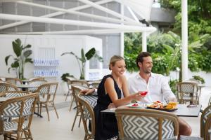Un uomo e una donna seduti a un tavolo con un bicchiere di vino di RACV Royal Pines Resort Gold Coast a Gold Coast