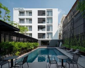 a swimming pool with chairs and tables in front of a building at Lilit Bang Lumphu Hotel in Bangkok