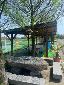 un refugio de picnic con una mesa y un árbol en Dongshan River Resort Farm, en Wujie