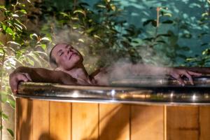 Un uomo steso in una vasca da bagno con vapore che esce di Escale Rochelaise, gîte urbain avec SPA bain nordique et sauna tonneau a La Rochelle