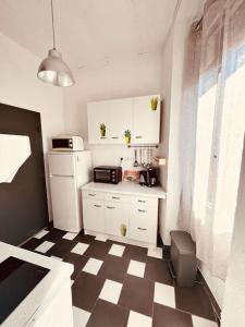 a kitchen with white cabinets and a checkered floor at Le Jean -Jaures 2 / Charmant P1 bis in Nîmes