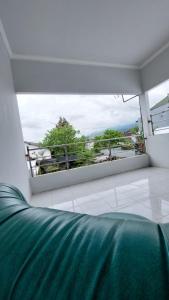 Habitación con sofá verde y ventana grande. en Dafaira holidayhome batu, en Tlekung