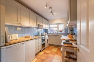 a large kitchen with white cabinets and blue tiles at Glastonbury, large House Stunning views 2 to 5 bedrooms, 3 receptions turn into bedrooms in Glastonbury