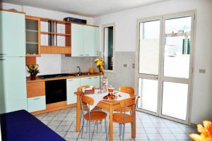 une cuisine avec une table et des chaises et une cuisine avec des placards blancs dans l'établissement Leuca Apartments - Happy Rentals, à Leuca