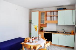 une cuisine avec une table et des placards blancs dans l'établissement Leuca Apartments - Happy Rentals, à Leuca