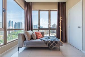 a living room with a couch in front of a large window at Dorsett Residences Sri Hartamas [5 Star Suites] in Kuala Lumpur