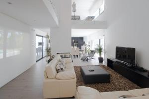 a white living room with a couch and a tv at Villa Alfazema IV in Aroeira