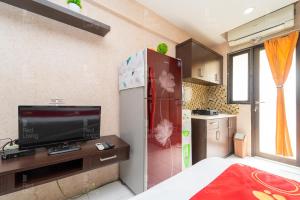uma pequena cozinha com uma televisão e um frigorífico em RedLiving Apartemen Kebagusan City - Nuna Rooms em Jakarta