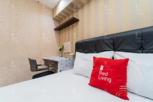 um quarto de hotel com uma cama com uma almofada vermelha em RedLiving Apartemen Kebagusan City - Nuna Rooms em Jakarta