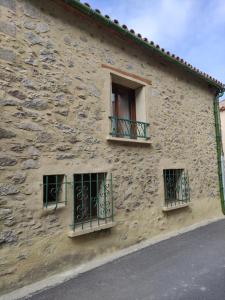 un edificio de piedra con tres ventanas. en Confortable maison de village en pierre typique, en Moltig les Bains