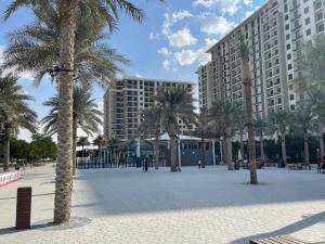 um pátio com palmeiras e um grande edifício em Town Square em Dubai