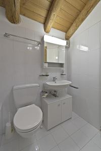 a white bathroom with a toilet and a sink at Chesa Suvretta - Celerina in Celerina