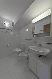a white bathroom with two sinks and a toilet at Chesa Suvretta - Celerina in Celerina