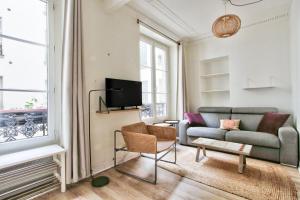 salon z kanapą i telewizorem w obiekcie Appartement Quartier Hotel de Ville Free Netflix w Paryżu