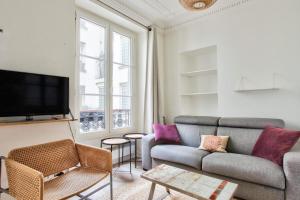 ein Wohnzimmer mit einem Sofa und einem TV in der Unterkunft Appartement Quartier Hotel de Ville in Paris
