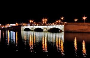 un pont sur une masse d'eau la nuit dans l'établissement Artemide Home, à Tarente
