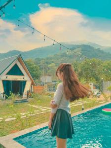 a young girl standing next to a swimming pool at Cloudy Home - Venuestay in Hanoi