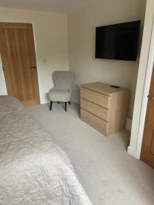 a bedroom with a bed and a chair and a television at High Hedges Apartment A in Oxford