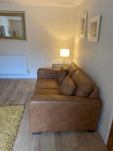um sofá castanho sentado numa sala de estar com um candeeiro em High Hedges Apartment A em Oxford