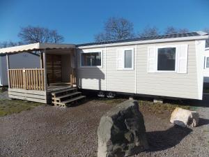 a white tiny house with a porch and a rock at Camping Insolite Le Haut Village in Saint-Michel-Chef-Chef