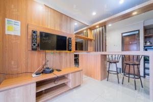 ein Wohnzimmer mit einem TV und einer Bar in der Unterkunft RedLiving Apartemen Gateway Pasteur - Sean Hospitality in Bandung