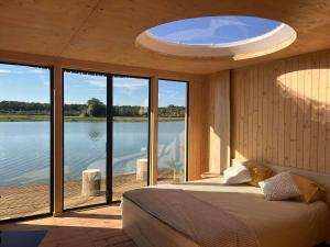 - une chambre avec un lit et une vue sur l'eau dans l'établissement Aquascope Virelles - Logements insolites, à Chimay