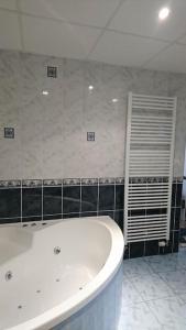 a white bath tub in a bathroom with black tiles at Au Coeur du Jura, Logement au calme in Champagnole