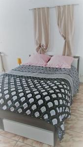 a bed with black and white sheets and pink pillows at Au Coeur du Jura, Logement au calme in Champagnole