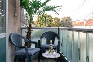 2 sedie e un tavolo con bicchieri da vino sul balcone di Nadia&V a Marghera