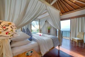 a bedroom with a bed with a view of the ocean at SIRI MENDIRA BEACH VILLAS (Villa Angsoka, Villa Bakung and Villa Cempaka) in Candidasa