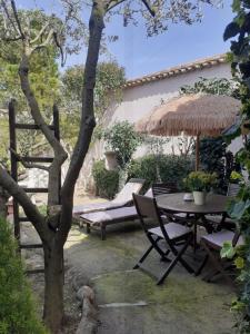 un patio con una mesa y una sombrilla de paja en La Sapiniére -chambres climatisées, en Buisson