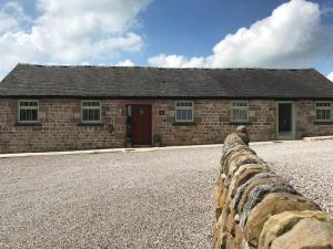 ein Backsteingebäude mit einer Steinmauer davor in der Unterkunft 2 Bed Stylish Peak District Cottage Barn Near Alton Towers, Polar Bears, Chatsworth House in Waterfall