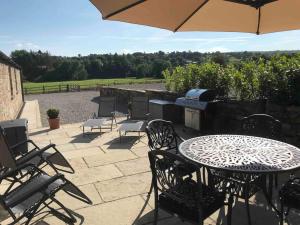 eine Terrasse mit einem Tisch, Stühlen und einem Grill in der Unterkunft 2 Bed Stylish Peak District Cottage Barn Near Alton Towers, Polar Bears, Chatsworth House in Waterfall