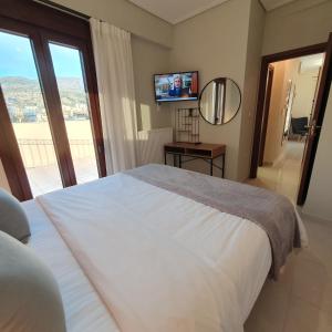 1 dormitorio con 1 cama blanca grande y TV en Volos Park Apartments, en Volos
