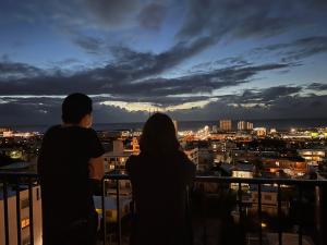 Una pareja mirando una ciudad por la noche en THE GRAND HOTEL GINOWAN, en Ginowan