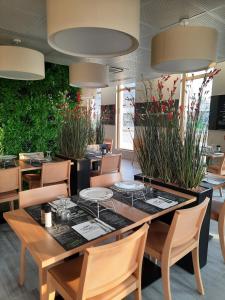 a dining room with a table and chairs and plants at The Originals Boutique Hôtel Amiens Sud in Amiens