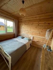 a bedroom with a bed in a log cabin at Vasaras Sapnis in Nidden
