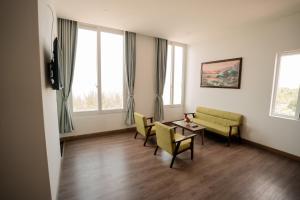 LÊ ĐOÀN HOTEL في راش غايا: غرفة معيشة مع طاولة وكراسي ونوافذ