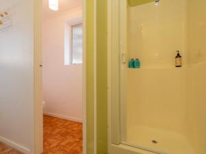 a bathroom with a shower with a glass door at Opito Sea'scape - Opito Bay Holiday Home in Opito Bay