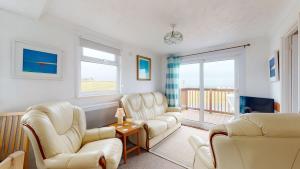 a living room with white chairs and a balcony at F62 Near Sea, Riviere Towans in Hayle