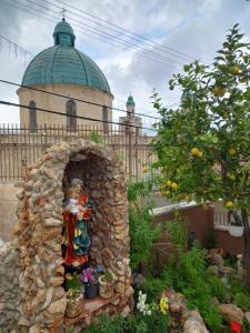 a statue of a woman in a garden in front of a building at Cana Wedding Guest House in Kafr Kannā