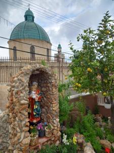 een standbeeld van een vrouw in een tuin voor een gebouw bij Cana Wedding Guest House in Kafr Kannā