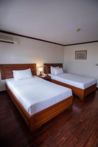 two beds in a room with wooden floors at Lao Orchid Hotel in Vientiane